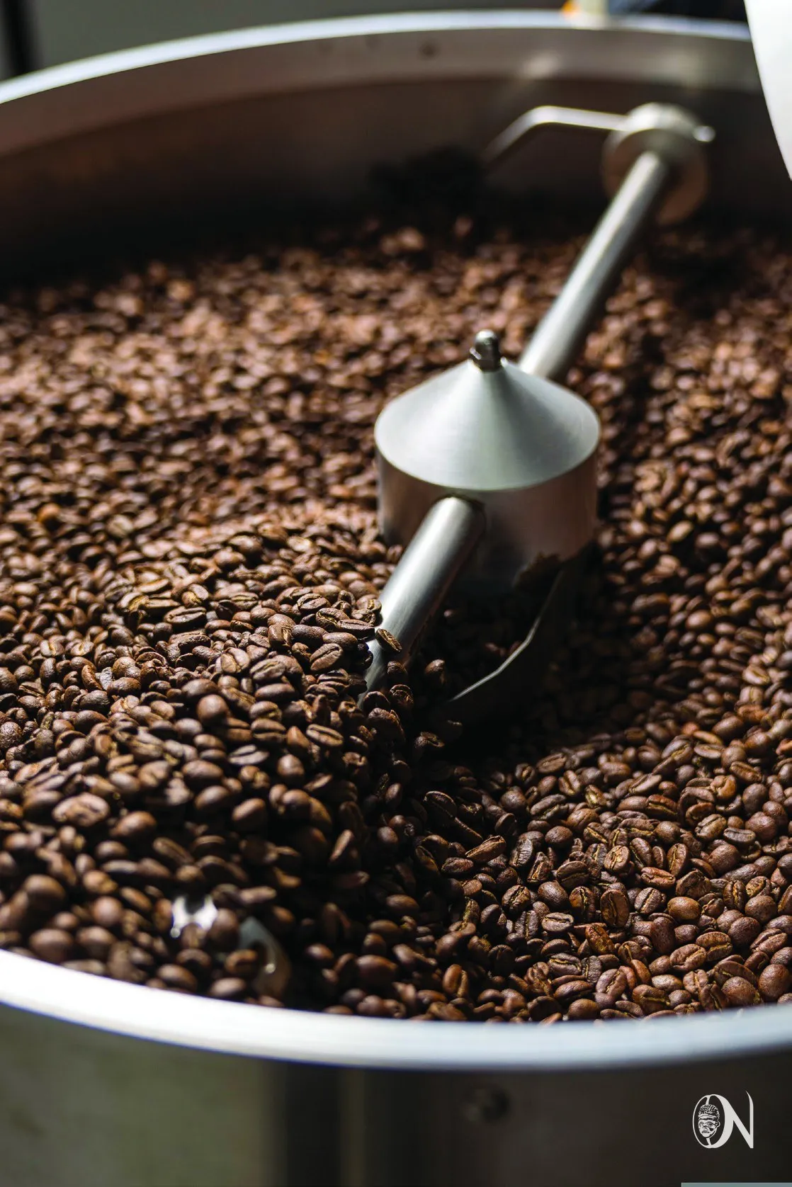 Freshly roasted beans turning in the cooling tray, scoop resting on top